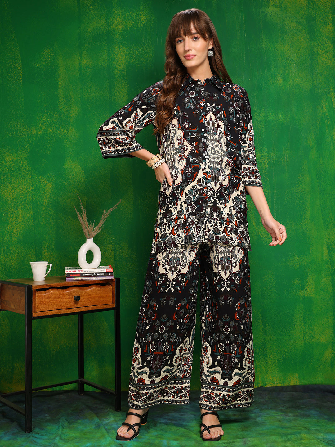 Woman wearing a black printed co-ord set with collar neck shirt and palazzo pants