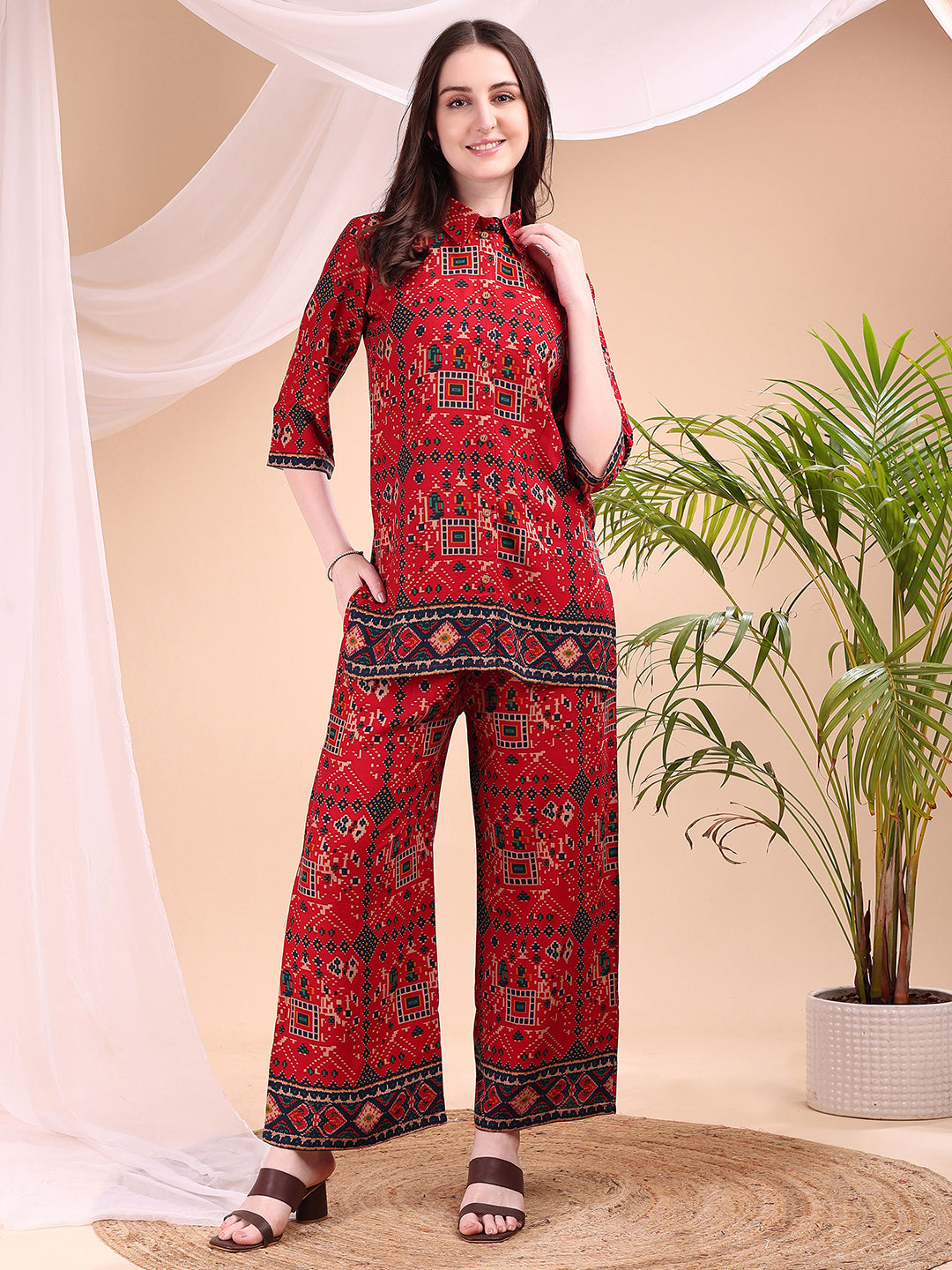 A woman wearing a vibrant red printed co-ord set consisting of a collar neck shirt and matching palazzo pants