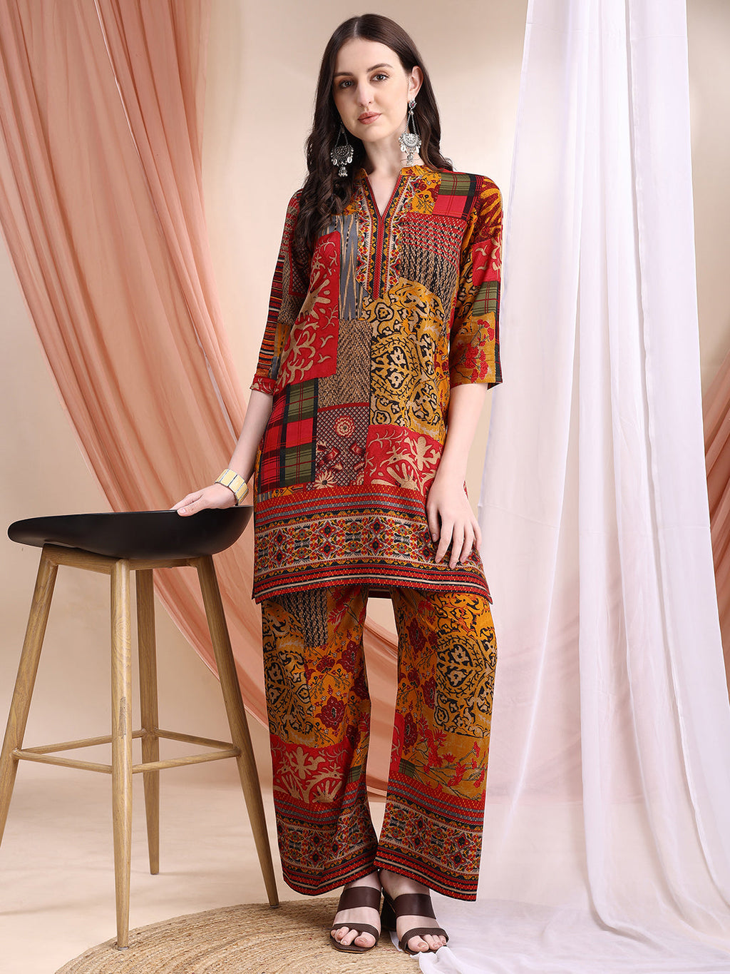 A woman wearing a vibrant red tunic and palazzo set featuring intricate floral and paisley print motifs.