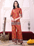 A woman wearing a vibrant red silk ethnic co-ord set with a collar neck tunic and palazzo pants.