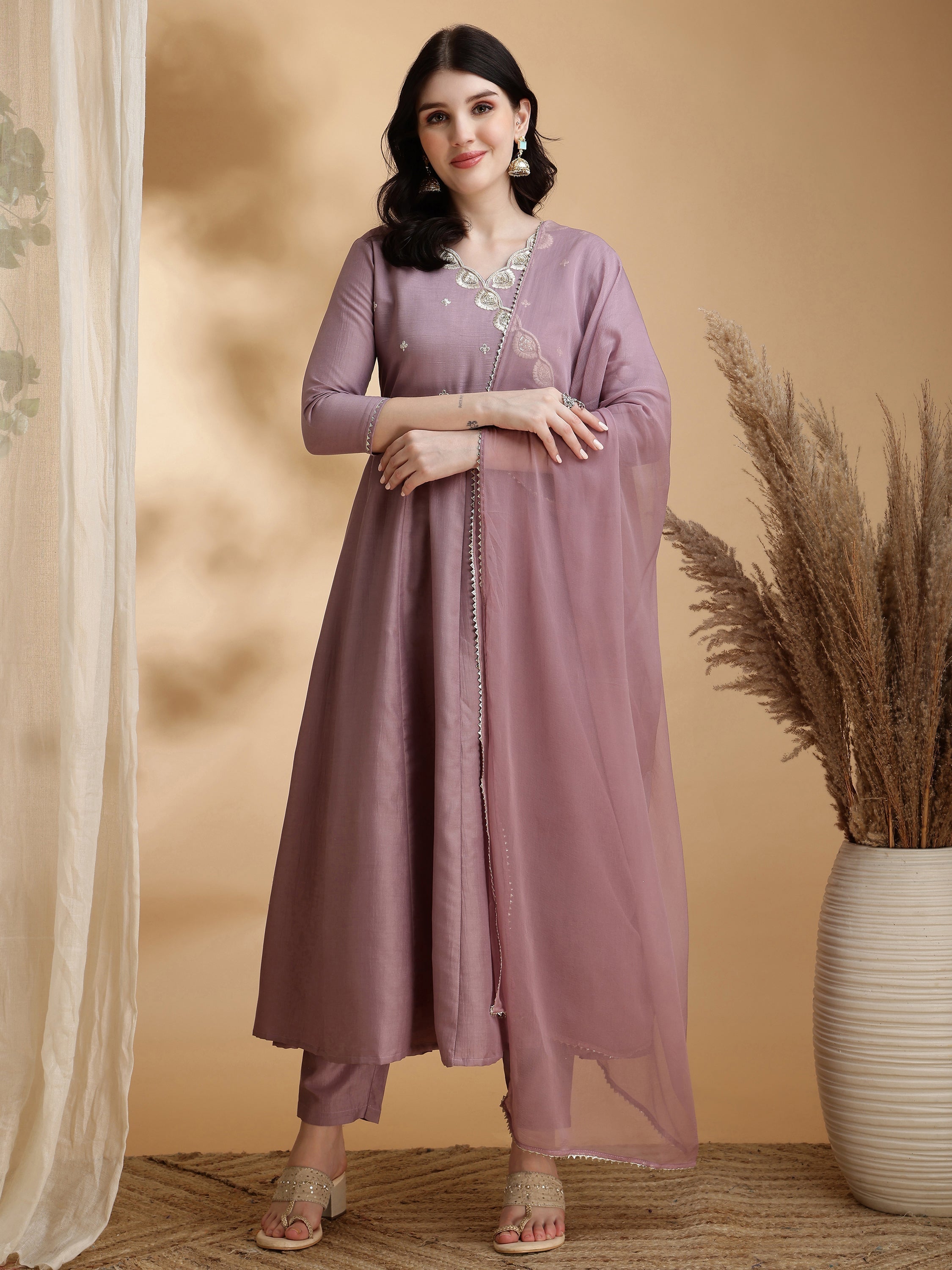 A mauve Angrakha-style Anarkali kurta set in chinnon fabric with intricate embroidery, paired with pants and a dupatta.