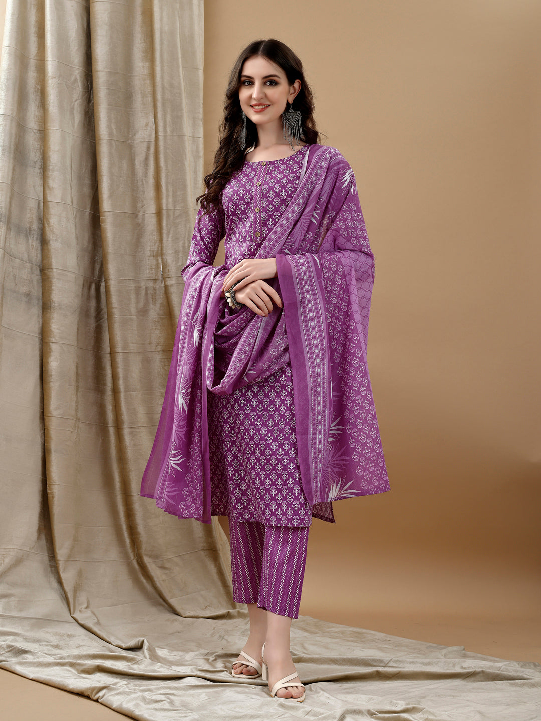 A purple cotton kurta set with ethnic motif prints, featuring 3/4th sleeves, matching pants, and a dupatta.