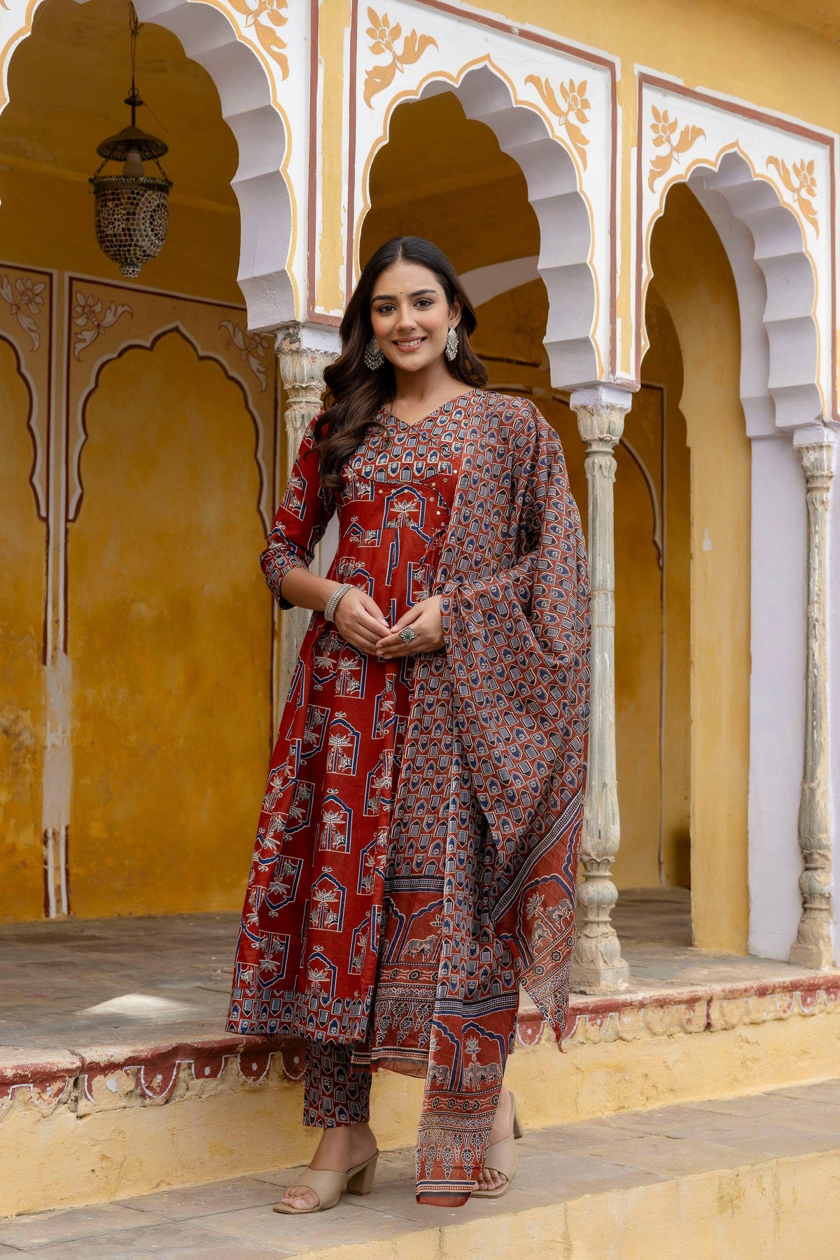 Woman wearing a Rust colored Ajrakh-inspired handblock printed Angarkha kurta set with matching dupatta