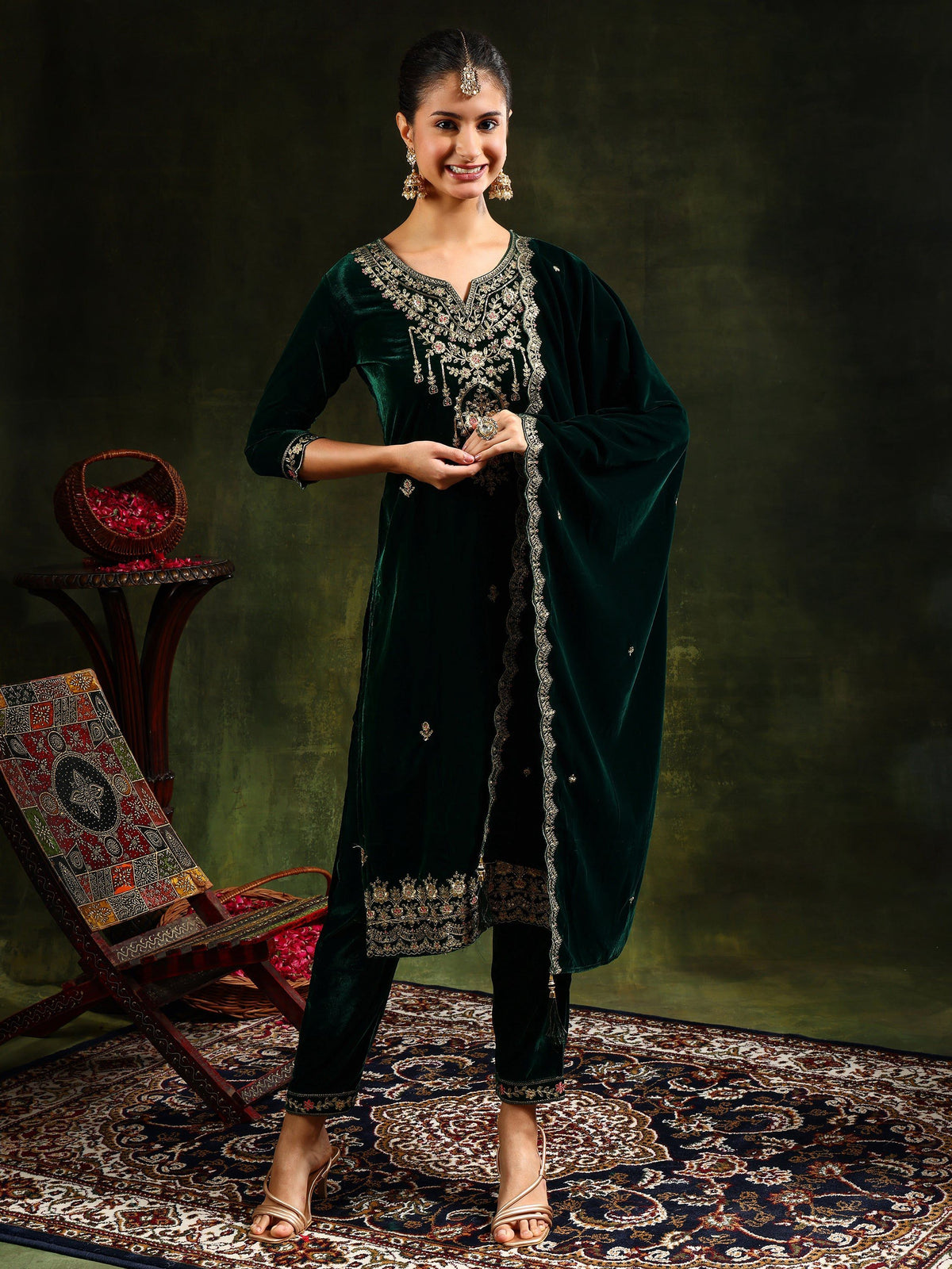 Woman wearing a green embroidered velvet kurta set with matching pants and dupatta