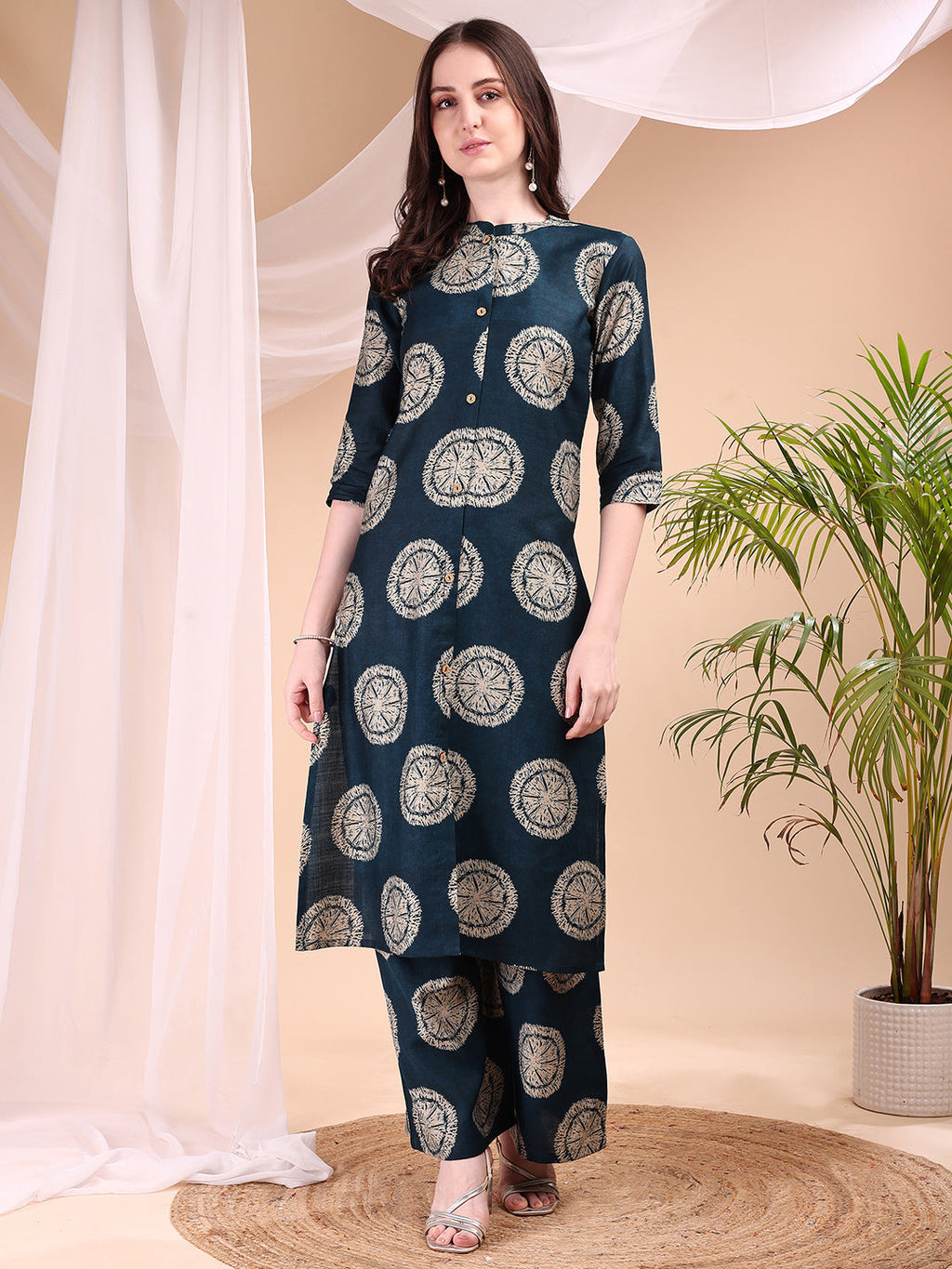 A woman wearing a teal silk-blend kurta and matching palazzo pants with ethnic printed motifs