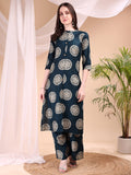 A woman wearing a teal silk-blend kurta and matching palazzo pants with ethnic printed motifs