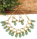 A luxurious green Kundan stone studded jewellery set with gold-plated alloy finish on a neutral background.