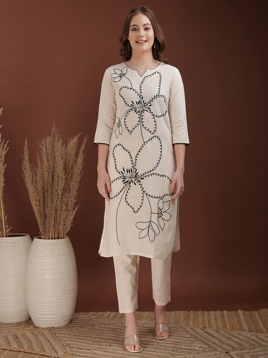 Woman wearing a white cotton co-ord set with floral embroidery and a sweetheart neckline