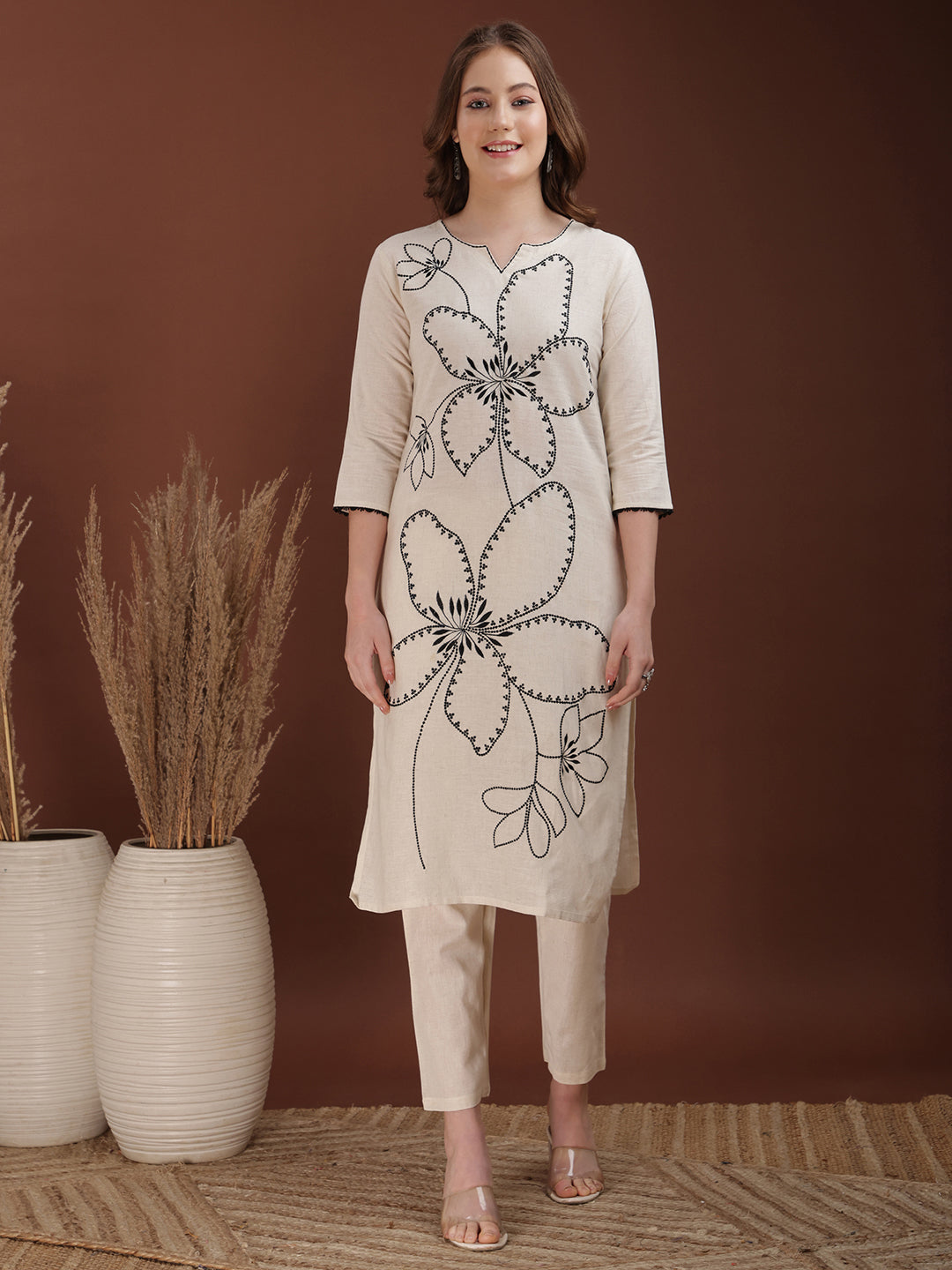 Woman wearing a white cotton co-ord set with floral embroidery and a sweetheart neckline
