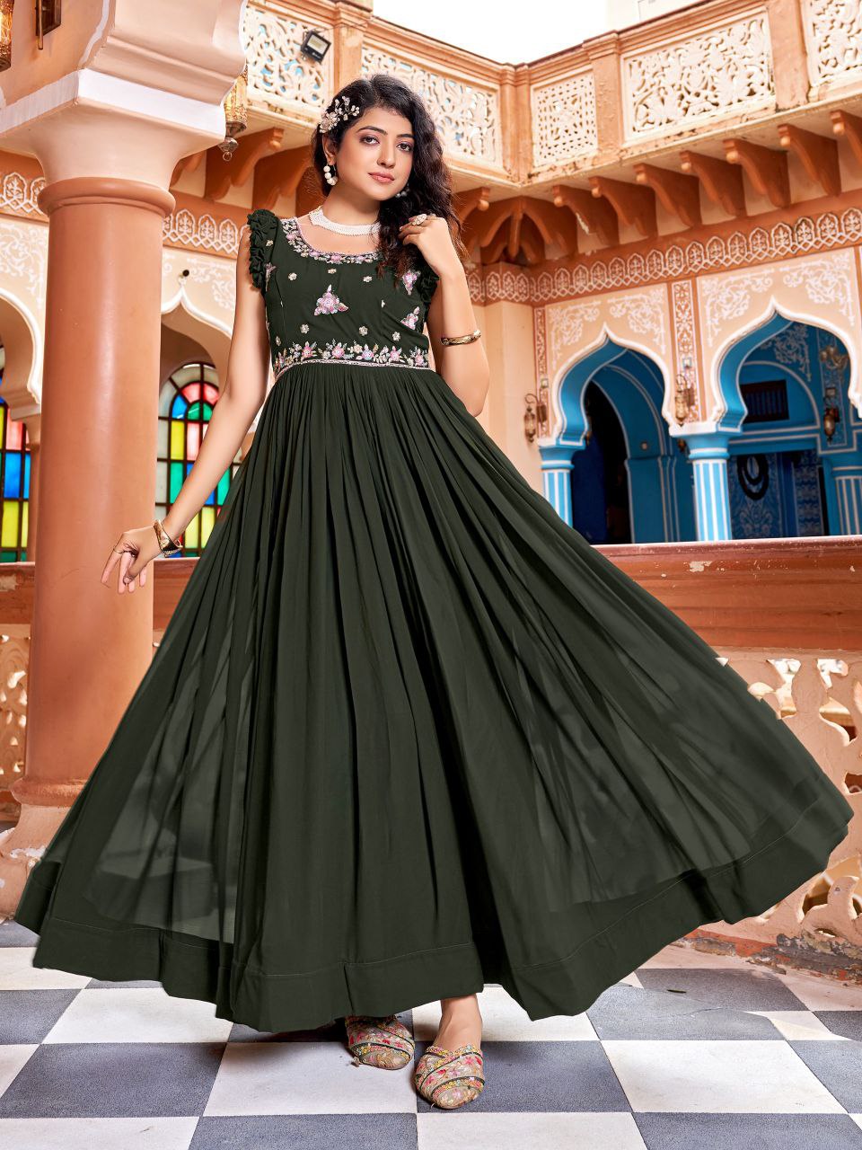 Woman wearing a floor-length dark green georgette gown with heavy zari and sequin embroidery work.