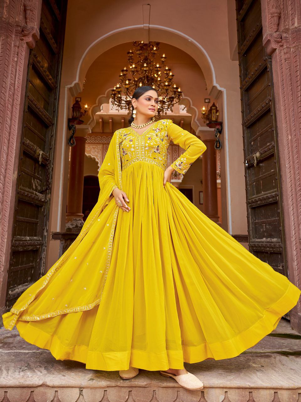 Model wearing a vibrant yellow georgette gown with intricate gold zari and sequins embroidery work