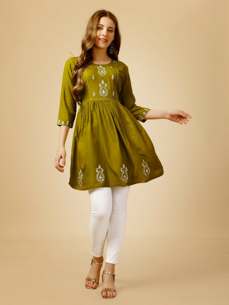 Woman wearing a mehendi-green A-line casual top with white embroidery and 3/4 sleeves