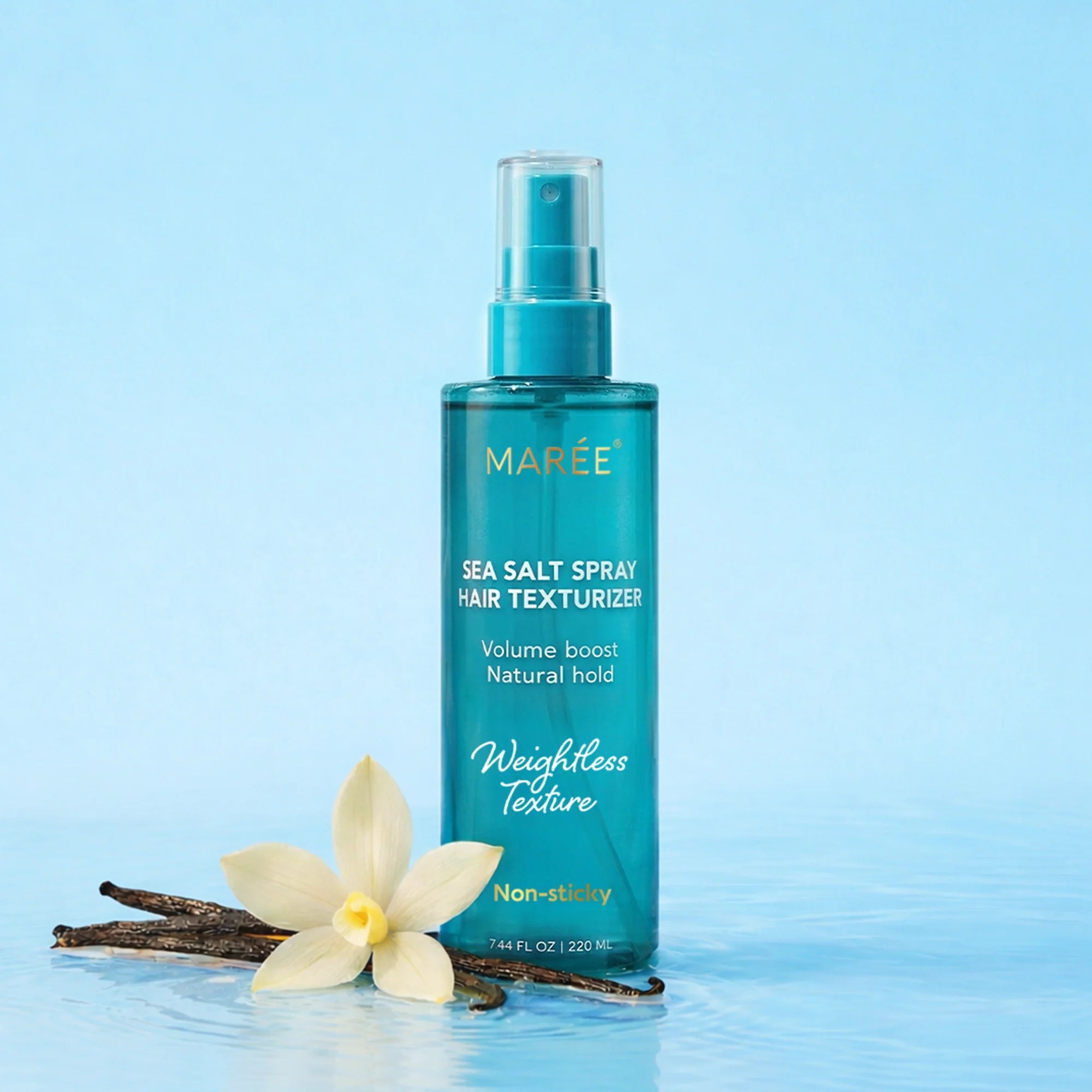 Bottle of Maree Keratin and Sea Salt Hair Texturizer spray next to vanilla bean and flower on blue background