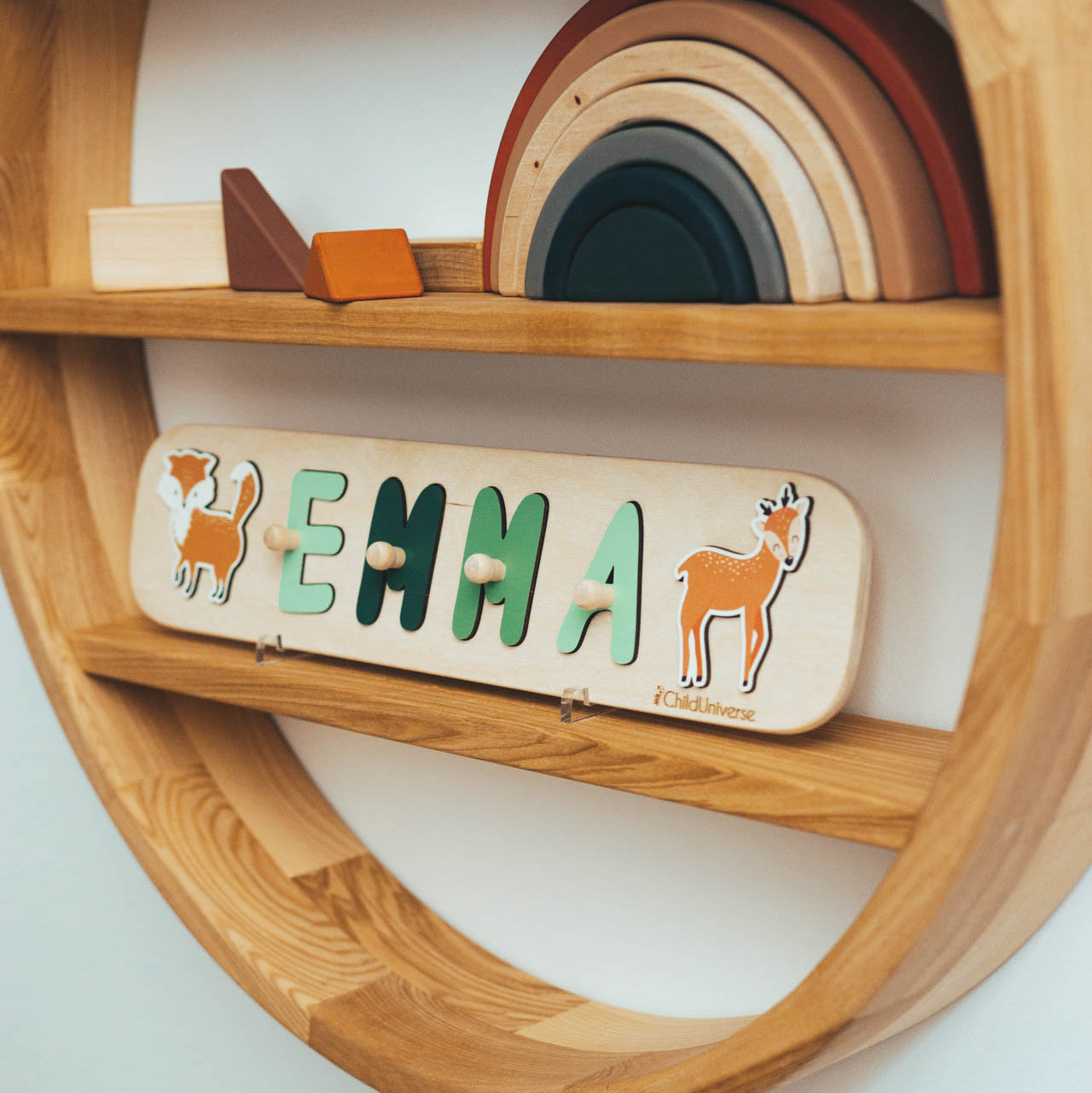 Personalized wooden woodland name puzzle with sage-green and forest-green animal accents in a minimalist style.