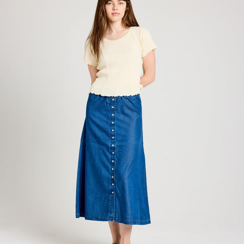 A woman wearing a blue midi length Tencel skirt with a button-down front and an elastic waistband.