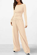 A woman wearing a matching beige long-sleeve top and wide-leg drawstring pants set