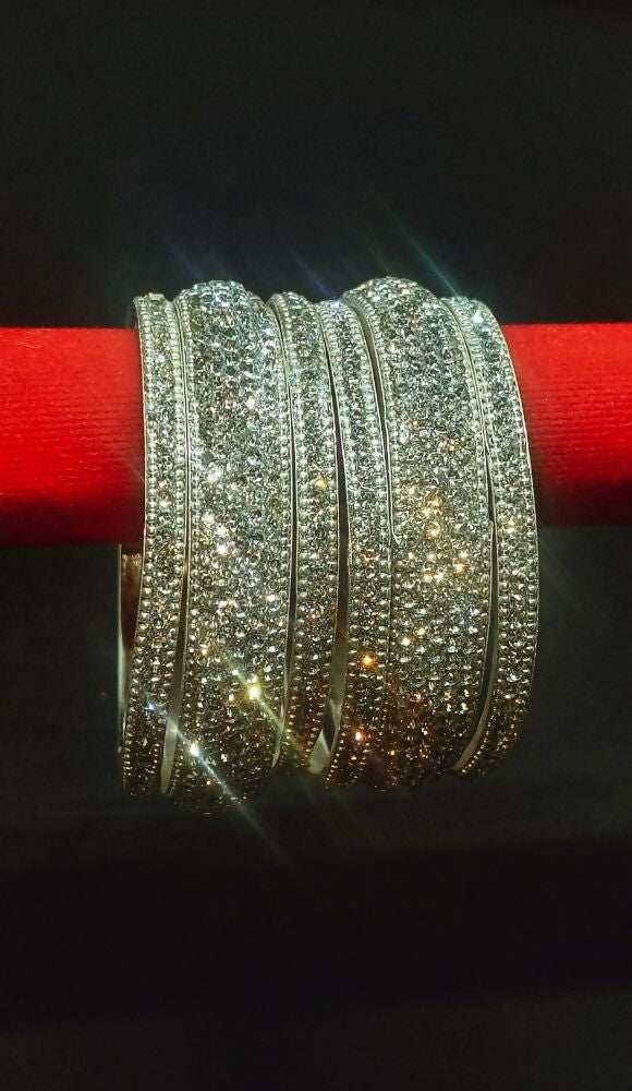 A set of silver-tone bangles adorned with sparkling clear crystals, elegantly styled for a sophisticated look.