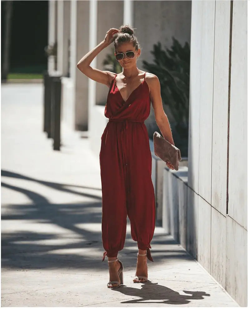 A woman wearing a floral print V-neck jumpsuit with cuffed ankles and tie-back details.