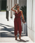 A woman wearing a floral print V-neck jumpsuit with cuffed ankles and tie-back details.