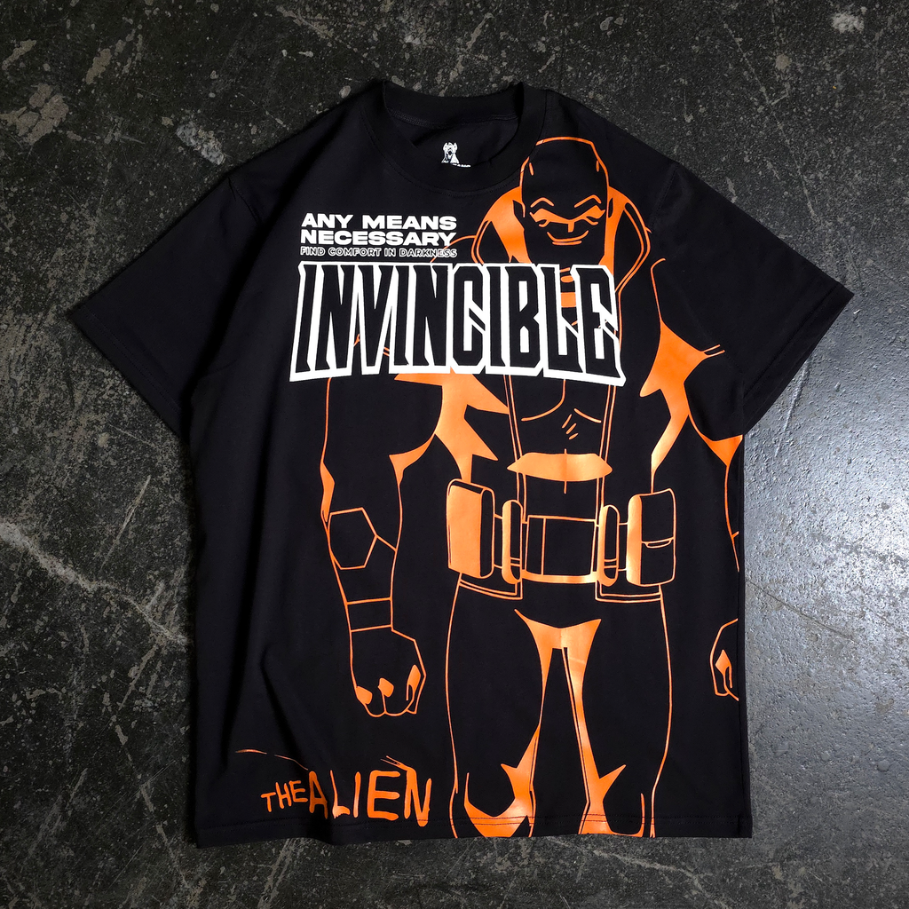 A man wearing a black graphic t-shirt with orange Invincible line art standing in a hobby shop