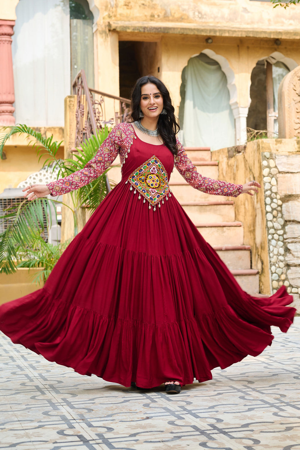 A maroon rayon gown featuring Kutchi Gamthi embroidery and colorful cotton print patterns.
