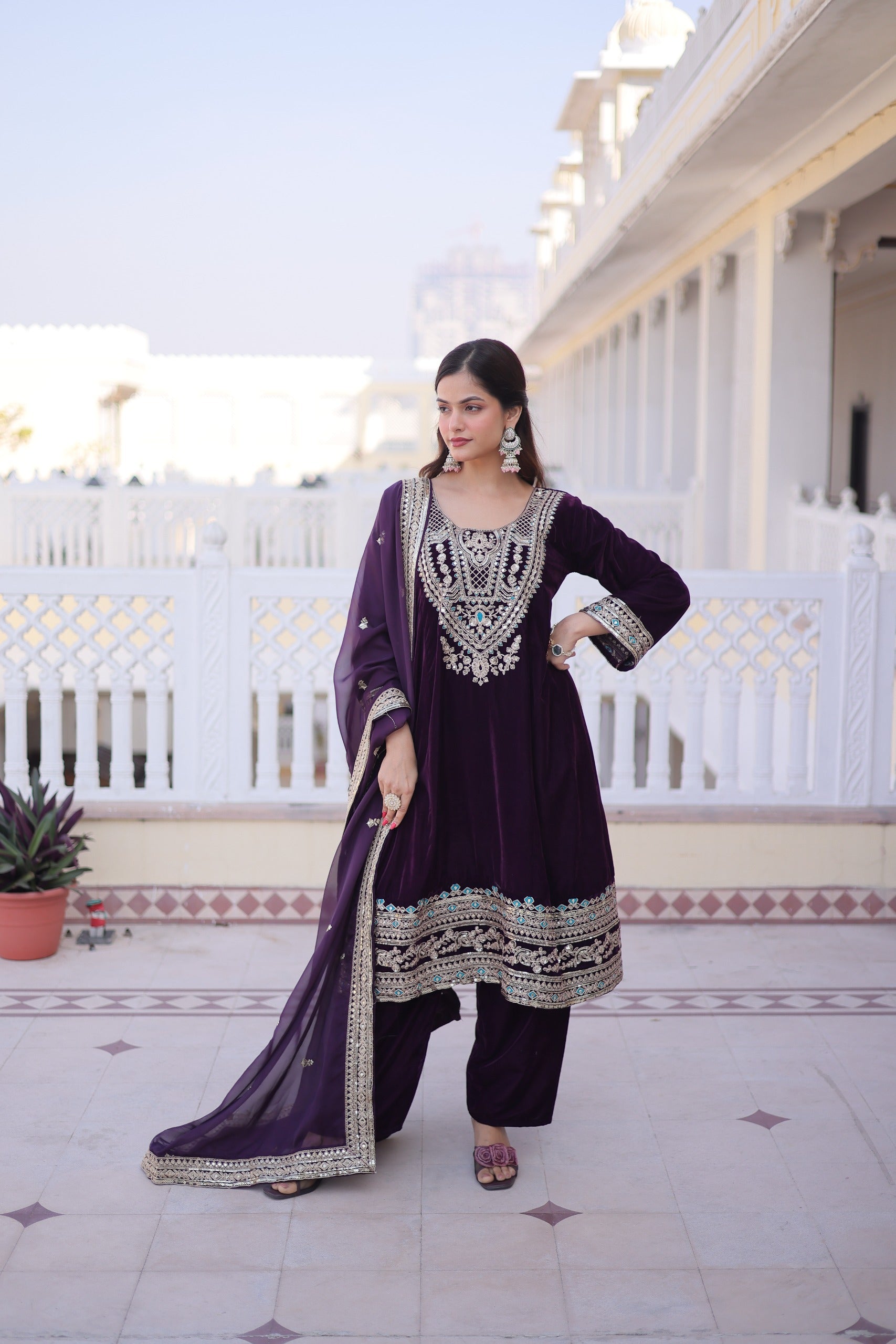 Wine-colored velvet salwar suit featuring detailed sequins, zari, and thread embroidery with bell sleeves.