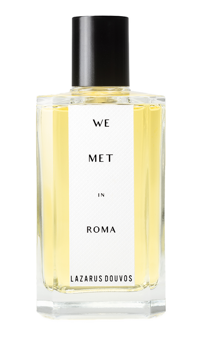 We Met in Roma Eau de Parfum in a minimalist transparent glass bottle with pale golden liquid.