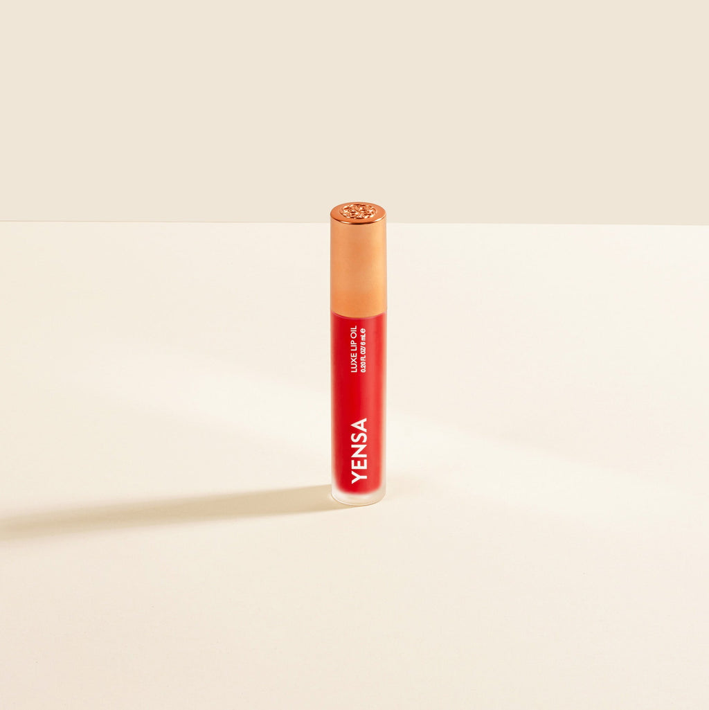 Yensa Luxe Lip Nourishing Oil bottle in red shade with gold cap on a neutral background