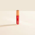 Yensa Luxe Lip Nourishing Oil bottle in red shade with gold cap on a neutral background