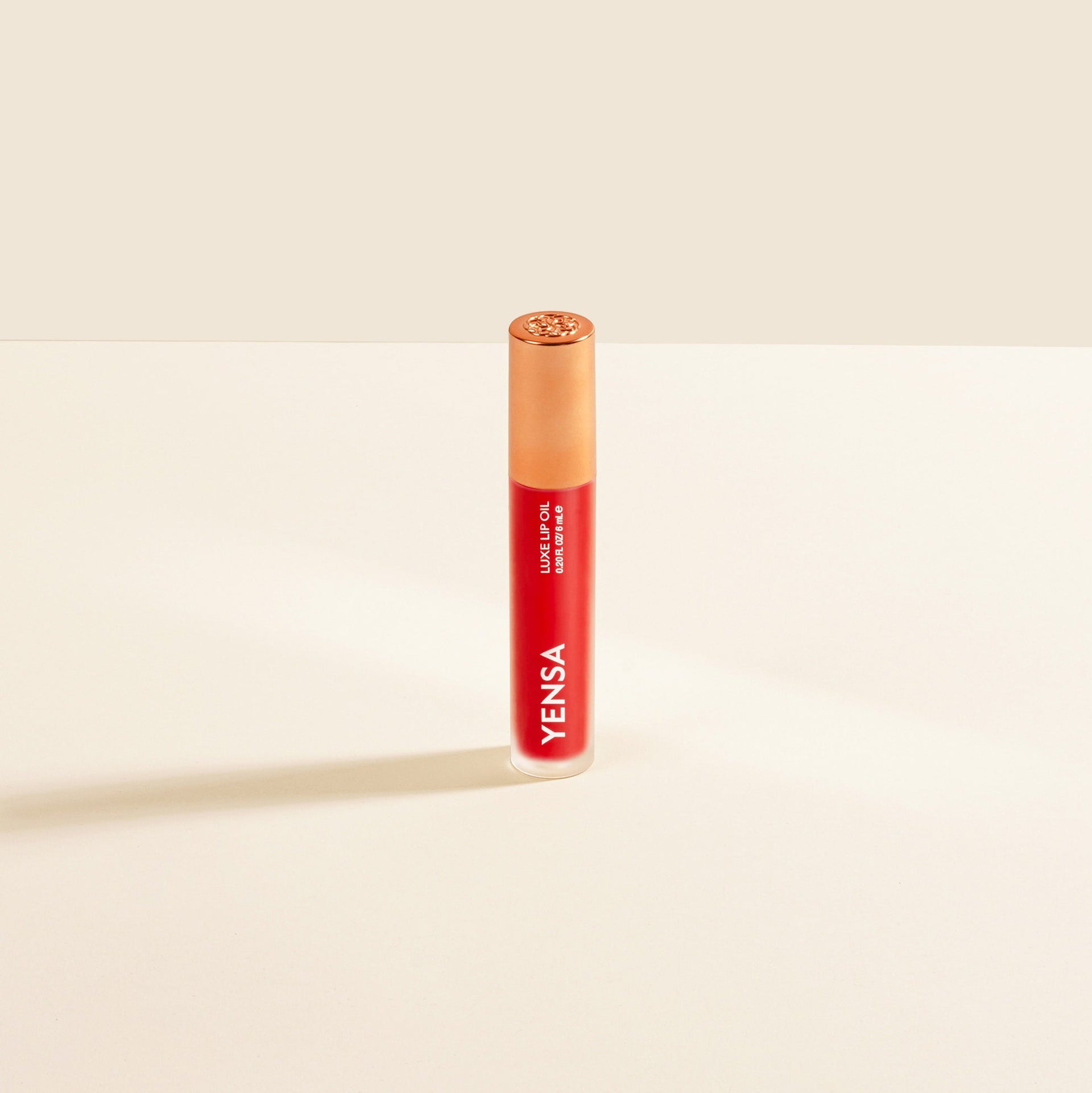 Yensa Luxe Lip Nourishing Oil bottle in red shade with gold cap on a neutral background