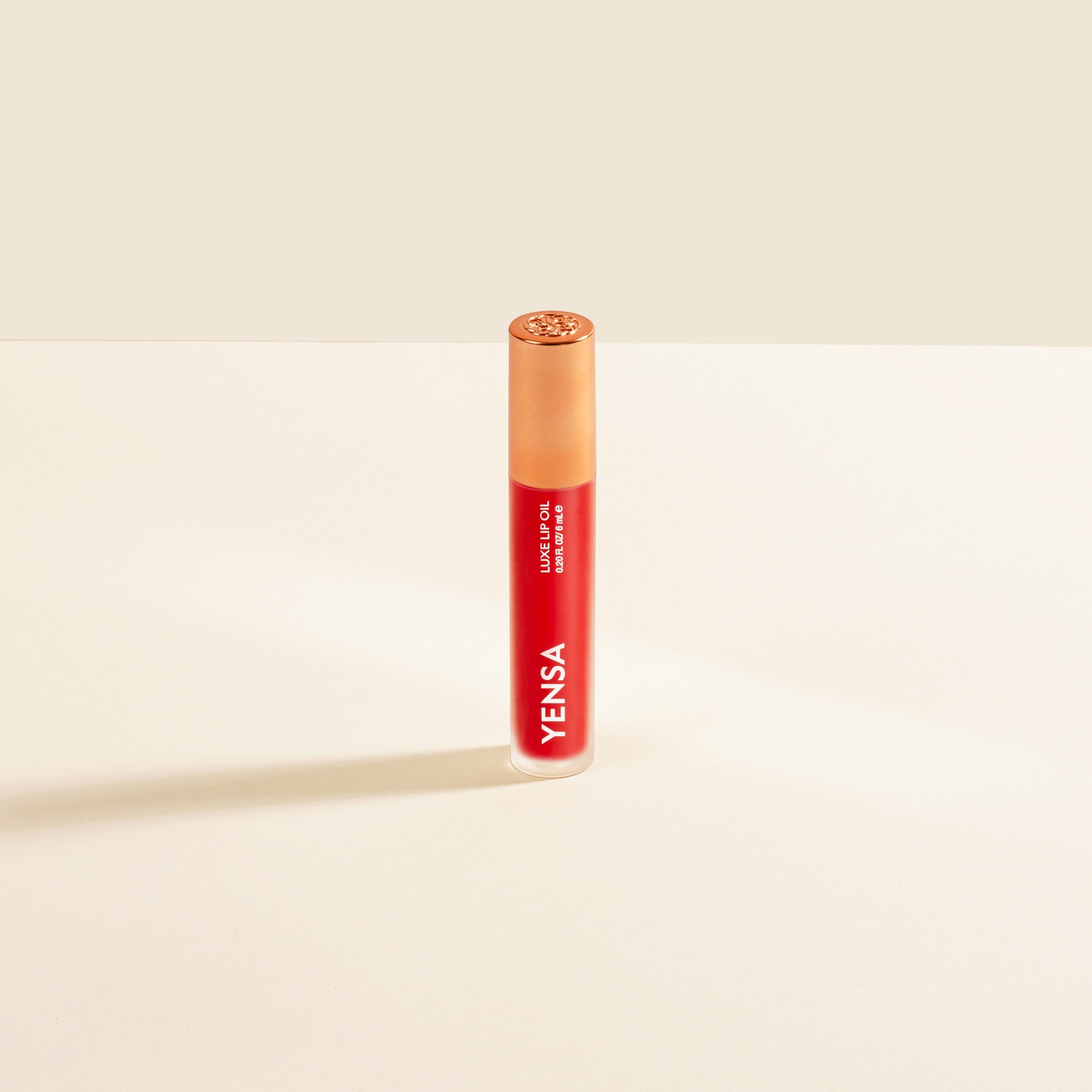 Yensa Luxe Lip Nourishing Oil bottle in red shade with gold cap on a neutral background