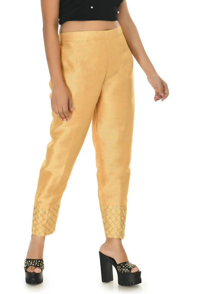 Close up of shimmering golden silk ankle length pants with tapered silhouette
