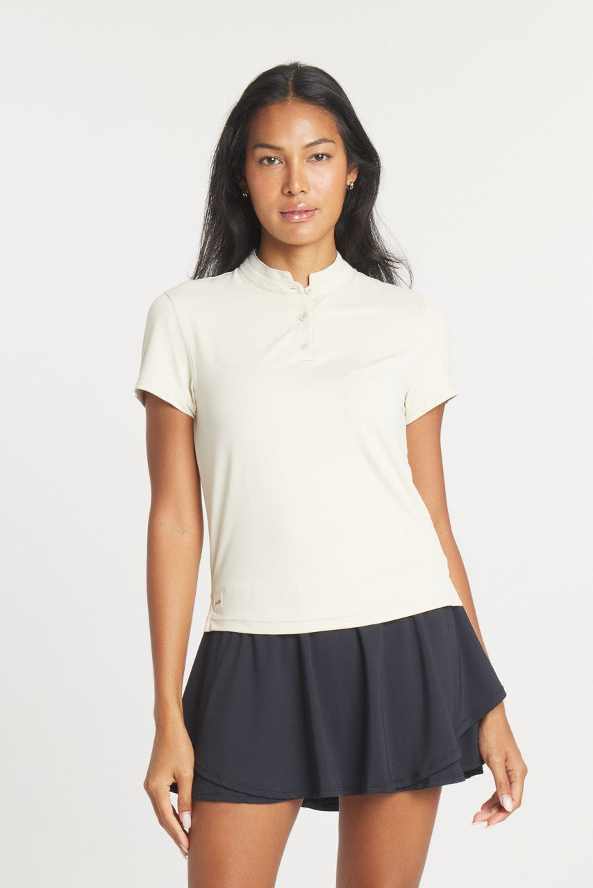 A woman wearing a Birch colored Catalyst Polo with a mock collar, styled for golf or casual wear.