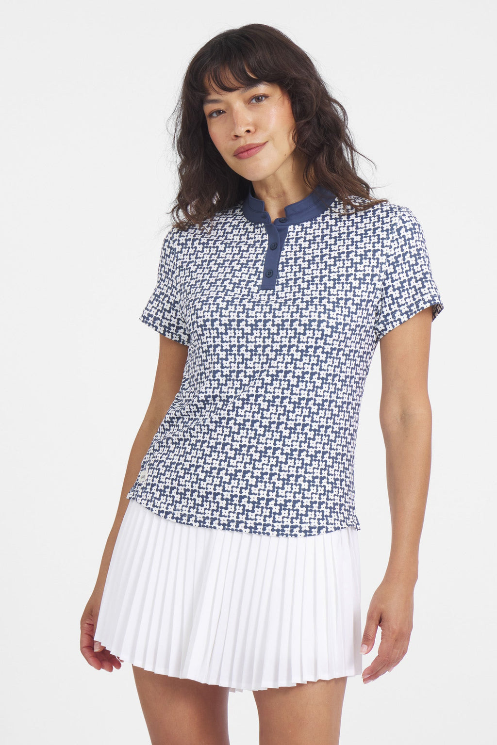 A woman wearing a white and navy blue floral print polo with a mock neck collar, paired with a white skirt.