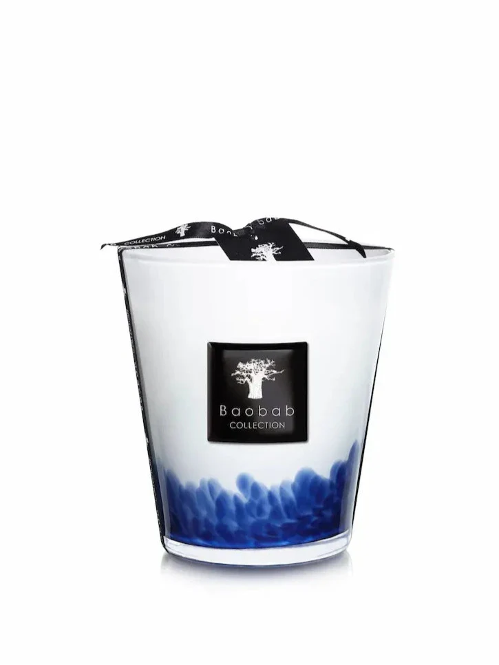 Close up of a Max 16 hand-blown glass candle with crisp white finish and deep blue organic feather-like ink patterns at the base.