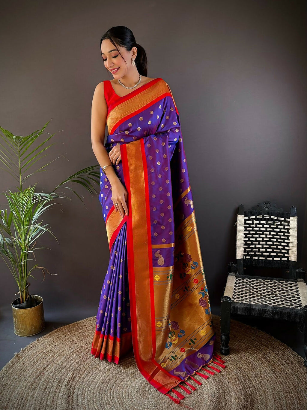 Model wearing a vibrant red Kanchipuram soft silk saree with intricate gold butti work and matching unstitched blouse.