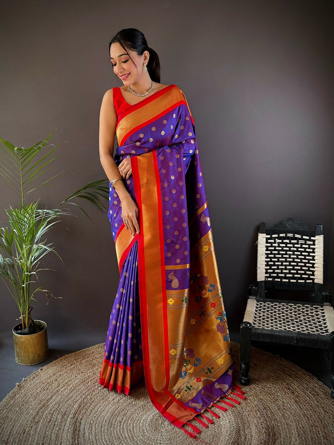 Model wearing a vibrant red Kanchipuram soft silk saree with intricate gold butti work and matching unstitched blouse.