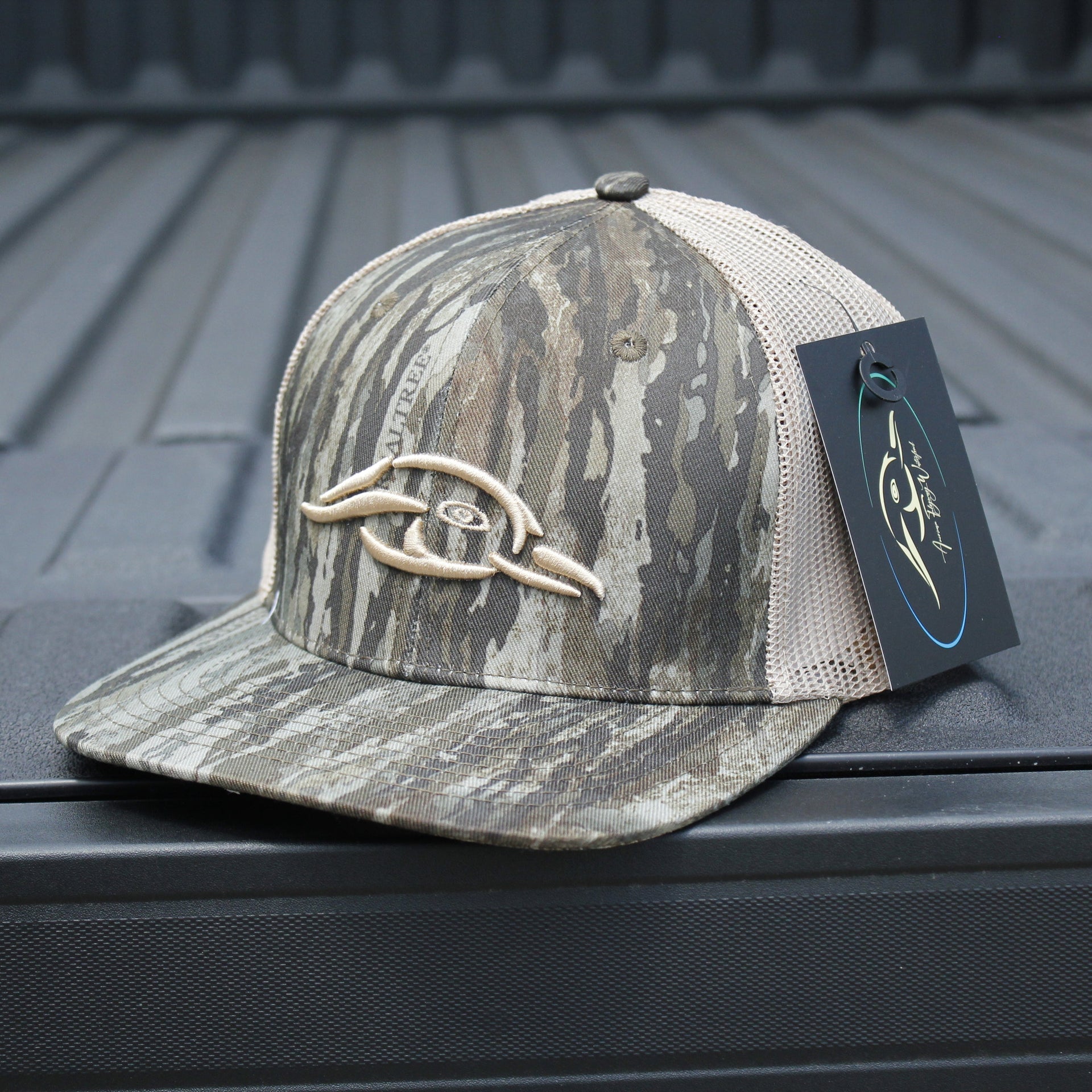 AFW Duck Logo Trucker Hat — side profile of Realtree Legacy camo cap with brand logo on a truck bed