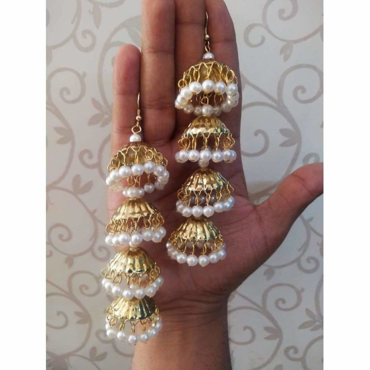 Traditional gold-polished latkan jhumka earrings featuring white pearl embellishments