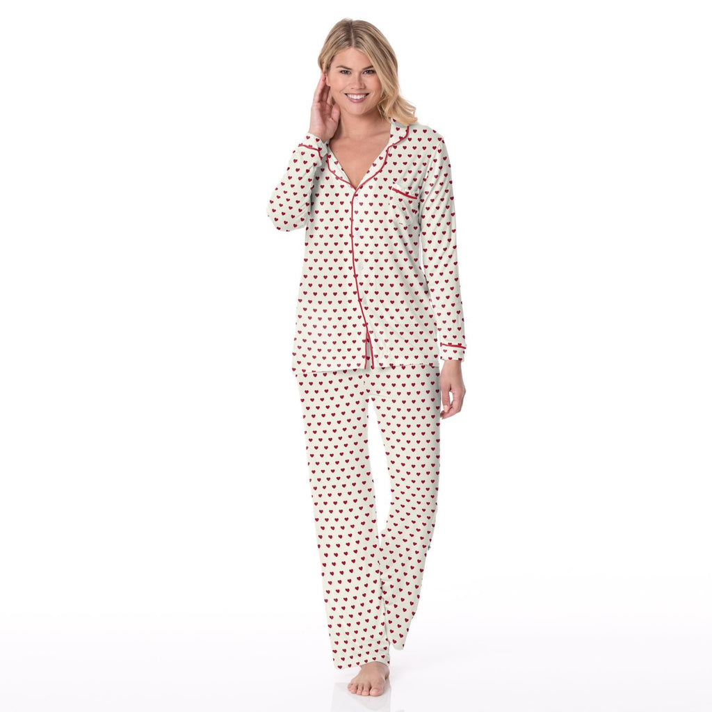 Woman wearing a women's long sleeve collared pajama set in a white and red heart print pattern.