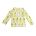 Woman wearing a zip-front long sleeve swim cover-up with a pineapple print on a beach.