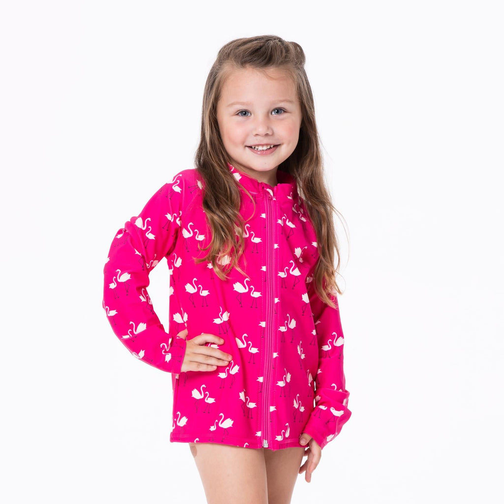 Girl's long sleeve zip-front swim cover up featuring a vibrant hot pink background with a white flamingo animal print pattern.