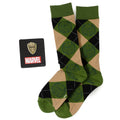 A pair of green, black, and tan argyle patterned socks with a Groot face design, next to a Marvel Groot character lapel pin.