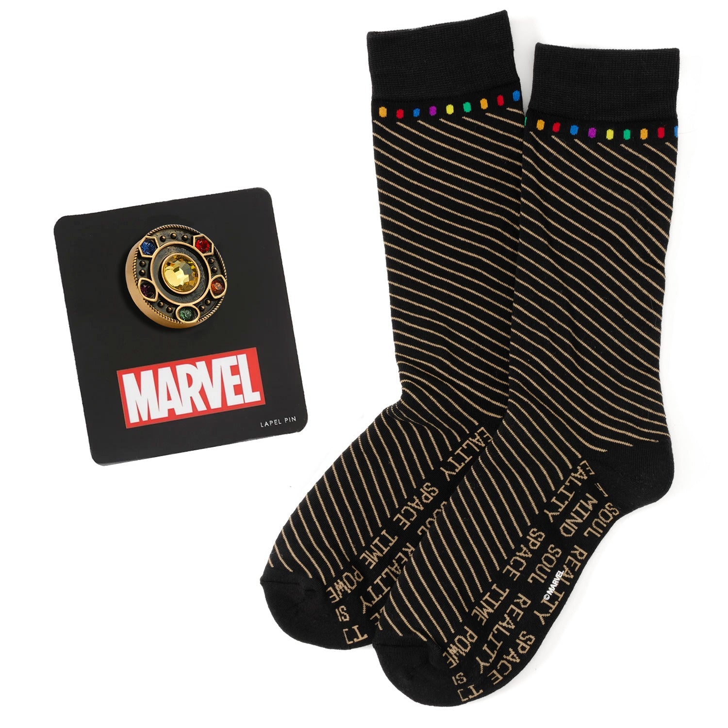 A pair of black crew socks with curved stripes and colorful Infinity Stone accents, displayed alongside an antique gold-tone Avengers lapel pin.