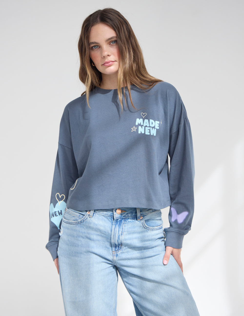 Model wearing a soft 100% cotton cropped long sleeve tee with a relaxed fit and dropped shoulders.