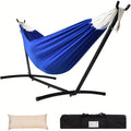 Blue double hammock with a black steel stand set up in a backyard setting.