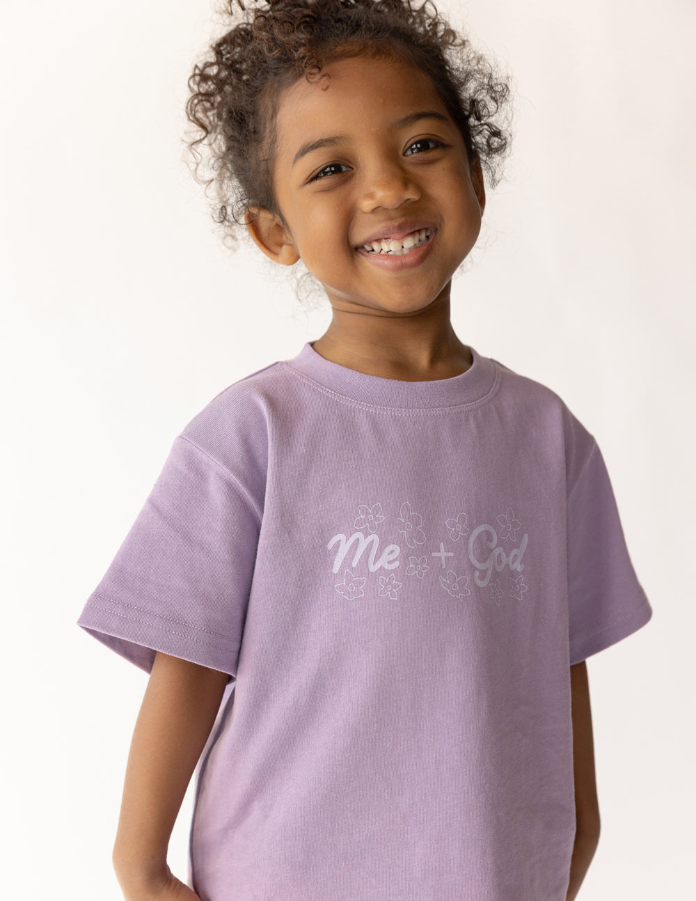 A child wearing a comfortable oversized Me Plus God graphic tee with a relaxed fit.