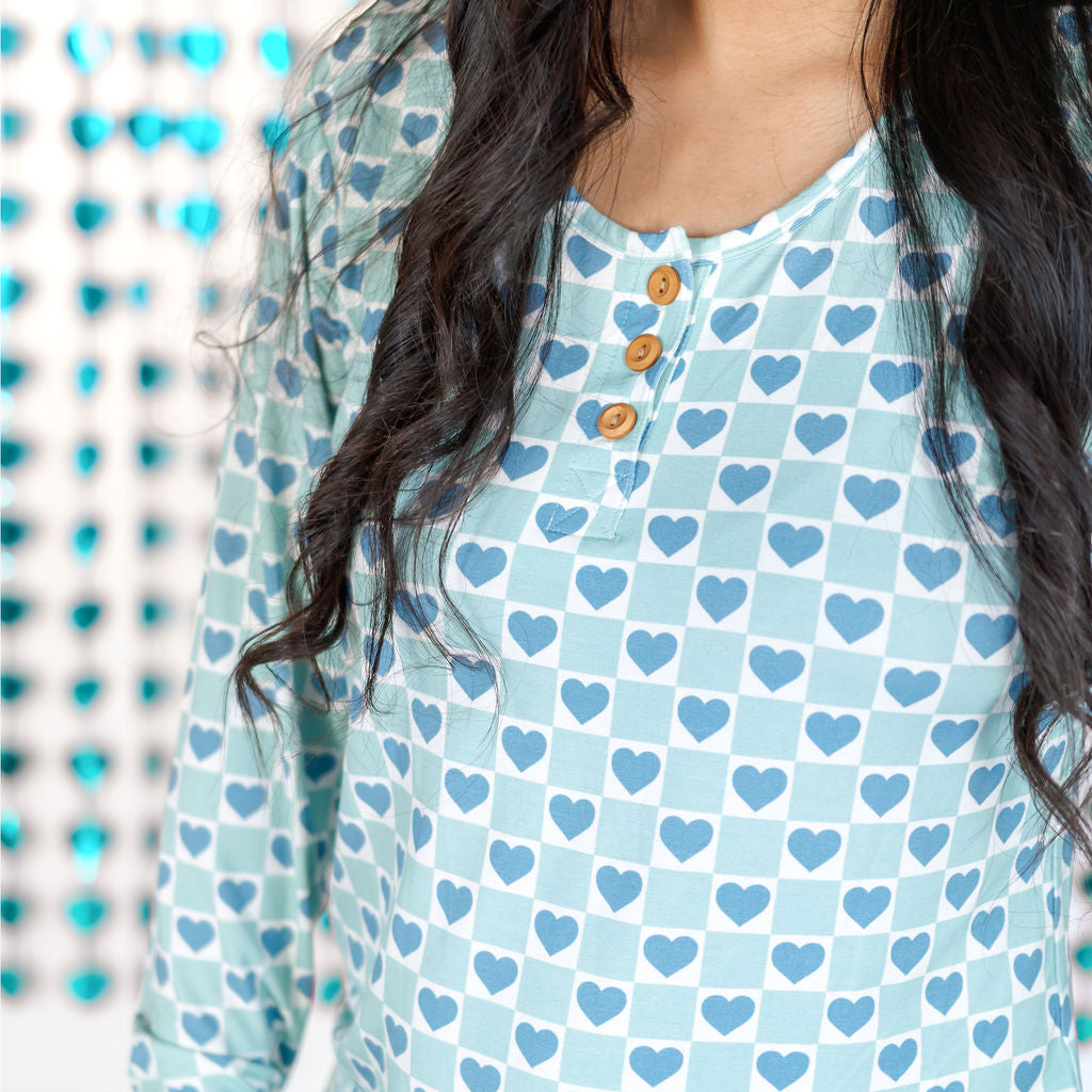 A woman wearing a long-sleeve blue heart pattern pajama set with a henley neckline and pockets.