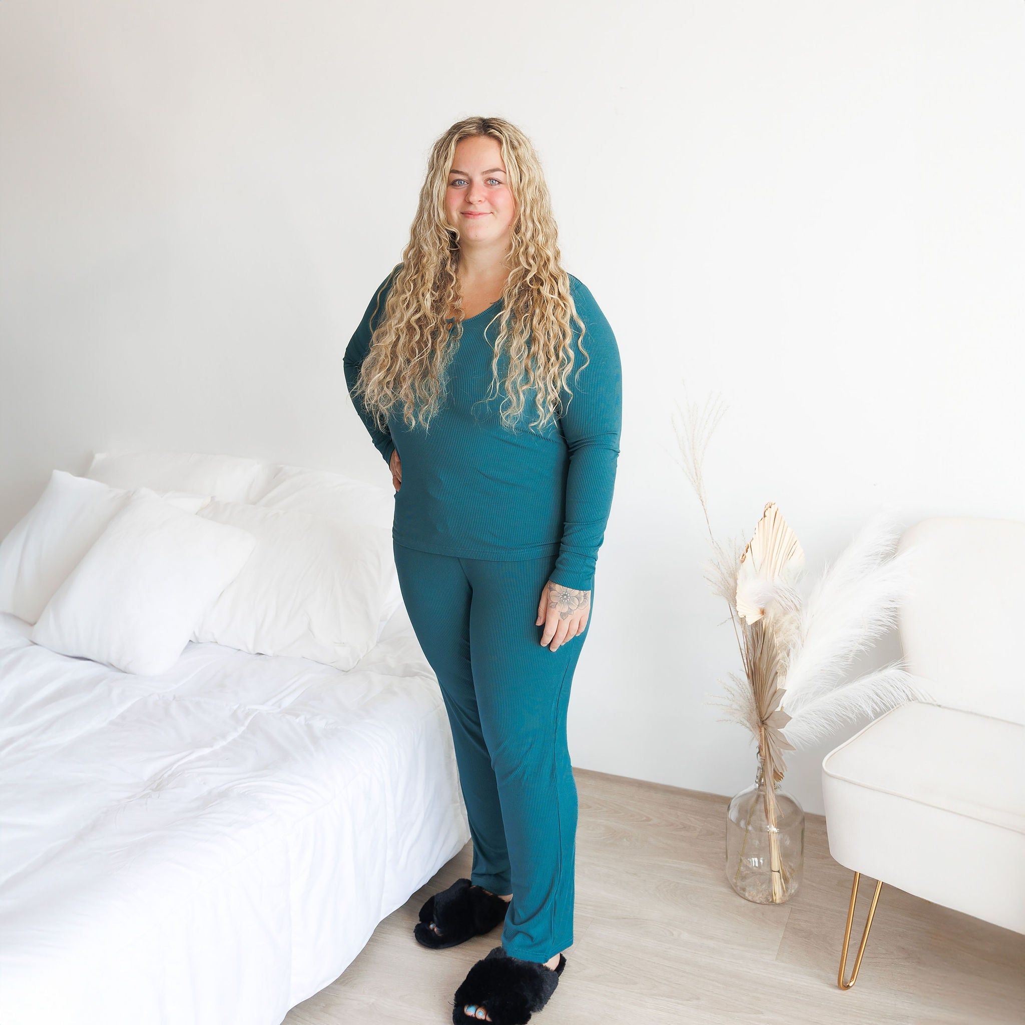 A woman wearing a long-sleeve ribbed peacock colored pajama set with henley button detail