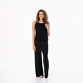 A woman wearing a black spaghetti strap camisole and matching wide-leg lounge pants in midnight, standing against a white background.